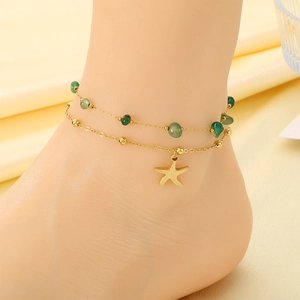 Detail of a gold double-layer anklet with green beads and a small starfish charm