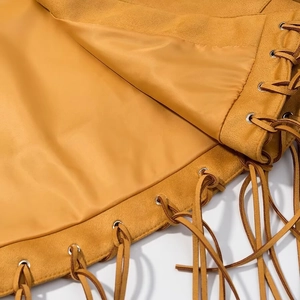 Detail of yellow faux suede fabric featuring fringe tassels and metal eyelets on cloak