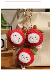 Detail of plush lychee keychain pendants with smiling faces on a cream tote bag