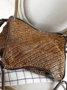 Brown woven paper straw shoulder bag with dark leather trim for casual beach vacations