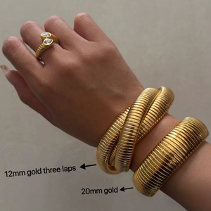 Three gold snake-style bracelets and rings in 18k plated titanium steel on female wrist