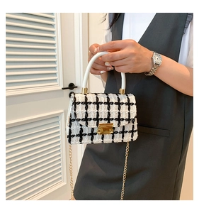 Gros plan du sac en tweed noir et blanc avec boucle dorée et poignée supérieure blanche