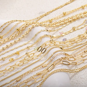 Macro shot of 18k gold plated chains featuring mixed link styles and colorful gemstones