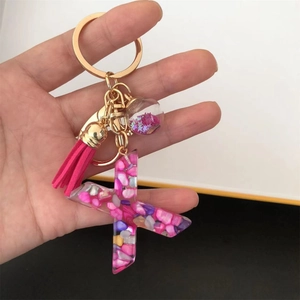 Detail of resin letter X keychain with pink tassel, glitter ball and gold metal ring