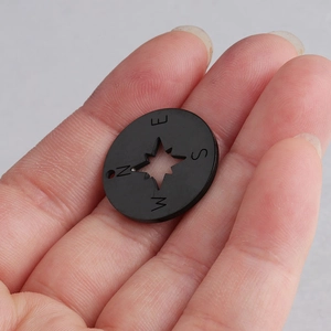 Detailed view of a 20mm stainless steel compass charm pendant with cutout star and N E S W