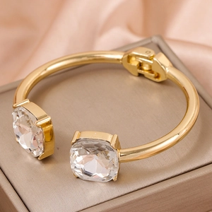 Elegant gold open bangle with dual cushion-cut crystals and hinged closure on silk