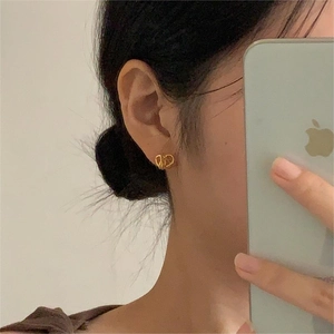 Detailed view of elegant gold-toned double C knot stud earrings worn on the earlobe