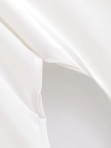 Detail shot of the white woven fabric seam and sleeve construction on the batwing dress