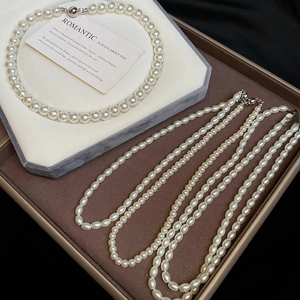Detail of round pearl choker and layered rice pearl necklaces on velvet background