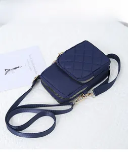 Detail view of navy blue quilted nylon crossbody phone bag with gold metal hooks and zippers