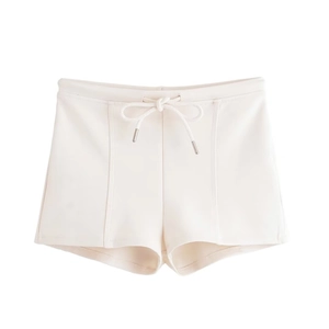 Close-up of cream drawstring shorts with high waist cut and metallic cord ends
