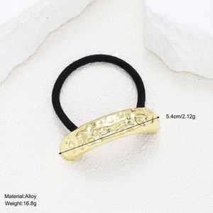 Detailed macro view of black elastic hair tie with irregular textured gold alloy charm
