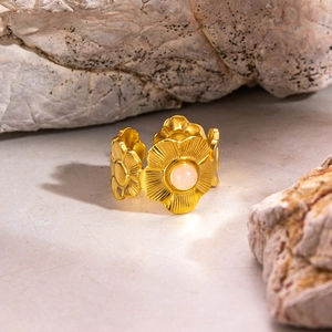 Gros plan d'une bague florale en acier doré 18K avec turquoise naturelle sur un rocher