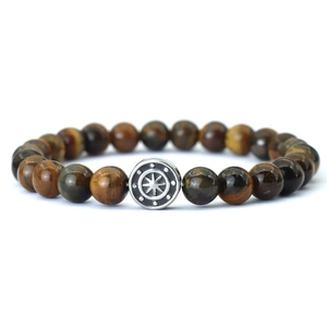 Macro shot of tiger eye beads bracelet featuring a vintage silver compass charm detail