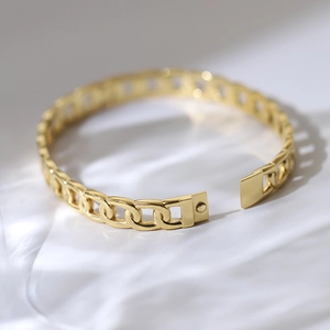 Detailed macro view of golden Cuban link chain bracelet on elegant white silk background