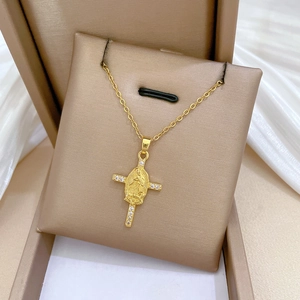 Close-up of gold-plated cross necklace with Virgin Mary relief and sparkling crystals