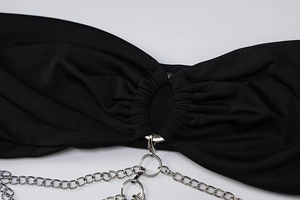 Detail van zwarte jurk met zilveren metalen ketting en centrale ringverbinding