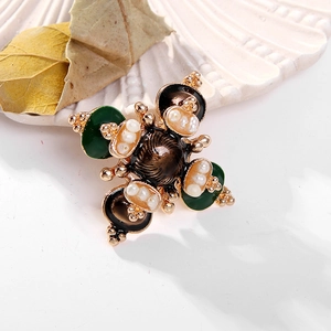 Baroque style golden cross brooch with green enamel and pearls on shell background