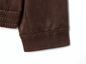 Detailaufnahme der dunkelbraunen Wildlederjacke mit gerippten Bündchen und Doppelnähten