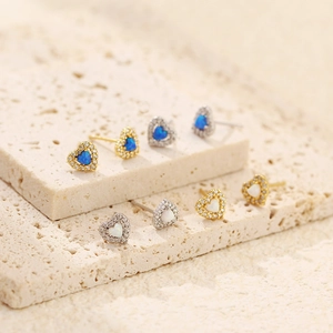 Detail of heart stud earrings featuring opal center stones and zircon border on stone
