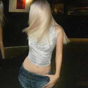 Sexy silbernes Glitzertop mit Neckholder und blaue Jeans in einer Club-Atmosphäre