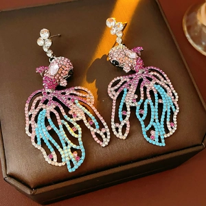 Gros plan de boucles d'oreilles vintage en forme de poisson avec cristaux roses et bleus