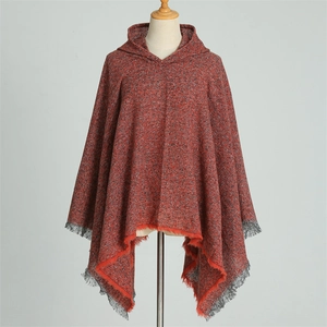 Close-up of red plaid hooded poncho featuring black fringe tassels and soft knit texture