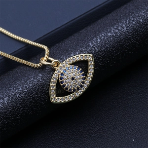 Macro shot of gold heart-shaped evil eye pendant with blue and clear crystals