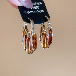 Macro shot of 925 silver hoop earrings featuring amber oval crystal fringe pendants