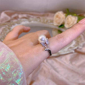 Macro detail of silver pearl ring with leaf design and zircons on pink satin cloth