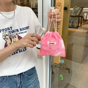Detailed close-up of pink tie-dye corduroy drawstring bag held by hand in soft natural light