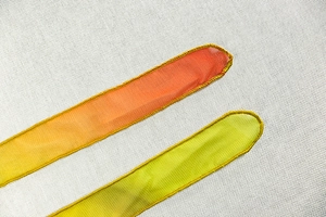 Close-up of vibrant pleated chiffon ribbons with fine stitching and gradient orange and green hues