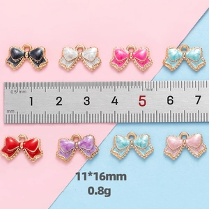 Detail view of colorful 11x16mm alloy bow pendants with ruler for size reference