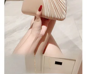 Detail of champagne gold evening clutch with pleated texture and thin metal chain strap