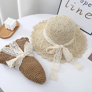 Close-up of summer straw hats with delicate lace bows and wavy brim texture details