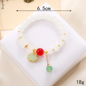 Détail d'un bracelet en perles avec breloque muguet et pendentif serrure ruyi verte