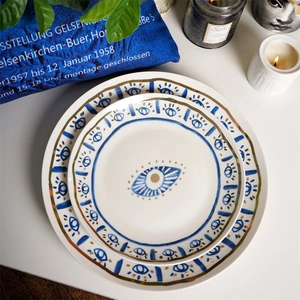 Flat lay of ceramic dessert plates with blue evil eye motifs and gold rim details