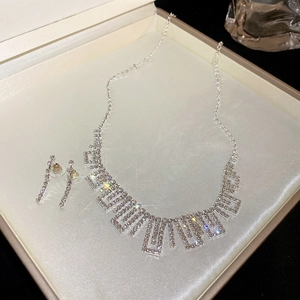 Close-up of sparkling silver rhinestone jewelry set with geometric tassel necklace