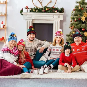 Festive LED Christmas knit hats with pom poms in a warm holiday fireplace setting