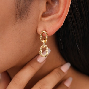 Gros plan de boucles d'oreilles dorées à double chaîne portées par un mannequin