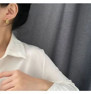 Close-up of triple-layered gold geometric earrings worn by a model in silk attire