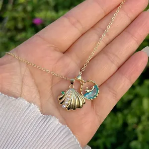 Close-up of 18K gold shell pendant with pearls and a blue stone sea themed charm