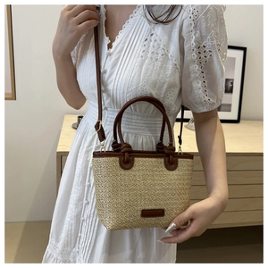 Detail of hand-woven straw tote with premium brown leather trim and detachable shoulder strap