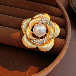 Detail of vintage golden flower brooch with large white pearl and sparkling crystals
