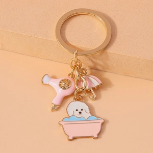 Close-up of golden keychain with enamel charms of a dog in a bathtub and a hair dryer