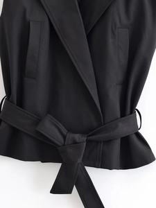 Gros plan détaillé de la ceinture réglable et du tissu tissé de ce gilet noir élégant