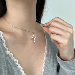 Detailed view of an S925 silver cross pendant featuring opal and blue zircon on a female neck