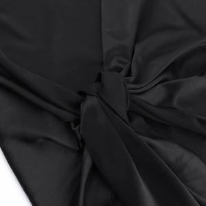 Macro detail of silky black satin fabric showing smooth texture and elegant drape