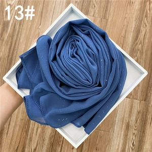 Détail d'un foulard en mousseline bleu foncé avec des paillettes dorées brillantes