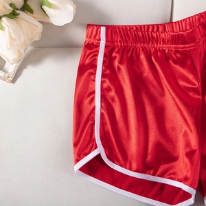 Detail of red satin sports shorts with white trim and silky glossy finish texture